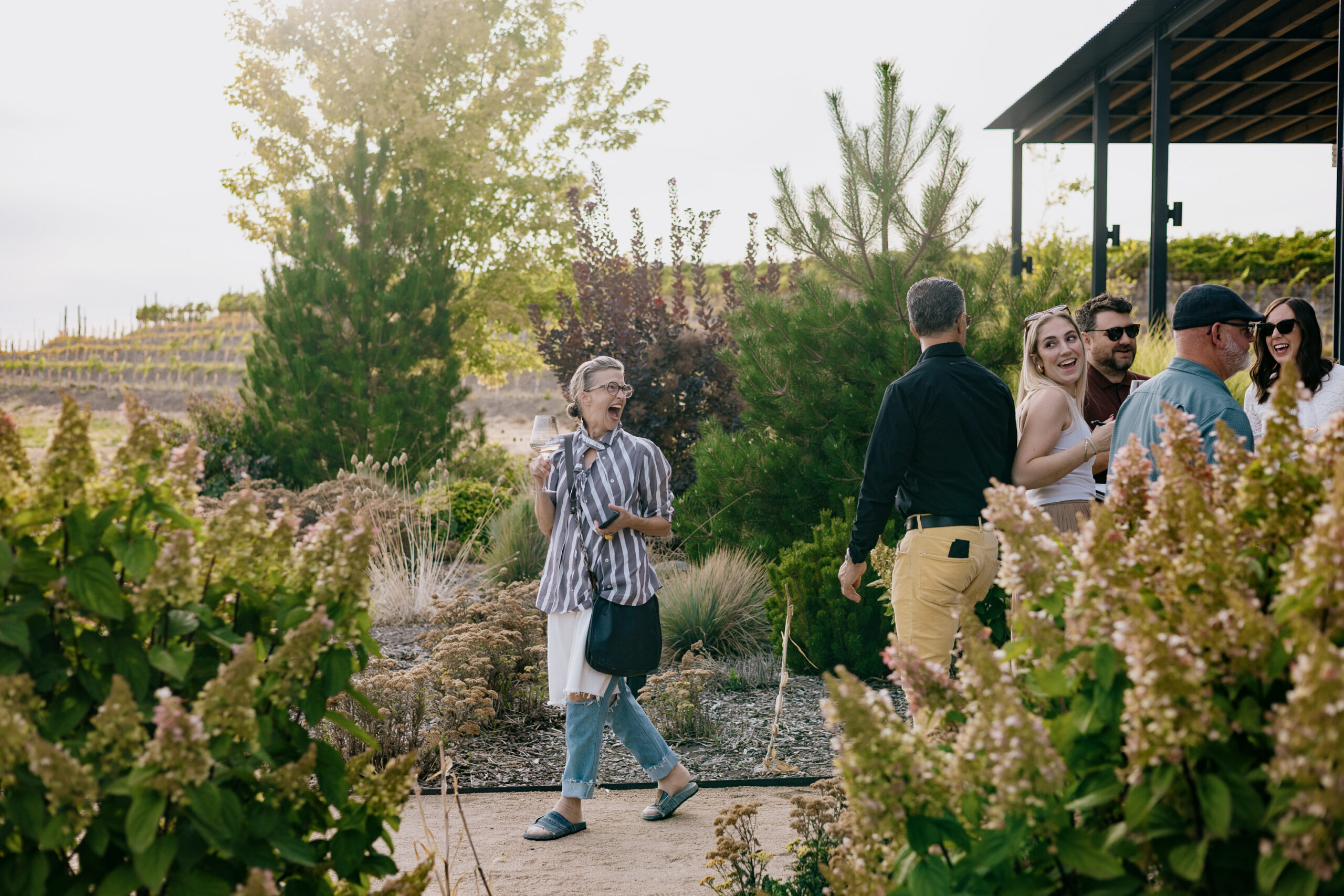 A guest laughing with a glass of wine in the Alton garden